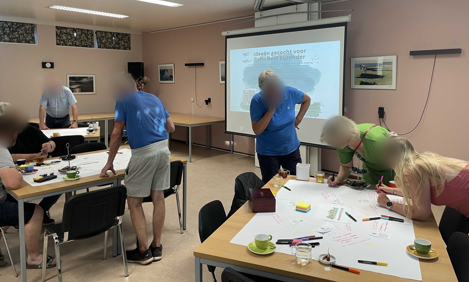 ov-baflo-werksessie-ondernemers-en-inwoners-geblurd Ondernemers en inwoners van Baflo schrijven staand en gebogen over tafels hun ideeën op grote vellen papier tijdens de werksessie